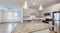 Located in Fort Myers, FL, this well-designed single-story home offers 2 bedrooms and 2 bathrooms within a thoughtfully arranged floor plan. The open-concept living area seamlessly connects the kitchen, dining, and living spaces, creating an inviting and functional layout. The kitchen is a standout feature, showcasing a striking granite island with bold veining, complemented by sleek gray shaker-style cabinetry, a textured white tile backsplash, stainless steel appliances, and a pair of elegant glass pendant lights overhead. Wood-look flooring runs throughout the home, adding warmth and continuity. The spacious primary bedroom benefits from multiple windows that invite abundant natural light, with a ceiling fan providing comfort year-round. Closets are equipped with wire shelving systems for organized storage. The hallway connects the bedrooms to two full bathrooms, maintaining a clean, efficient flow. A dedicated laundry area houses a full-size washer and dryer. The home also includes a private patio, ideal for enjoying the Florida climate. With its modern finishes, neutral color palette, and practical layout, this home offers a clean and comfortable living environment.
