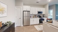 Located at 205 Rhyne Rd in Charlotte, NC, this single-floor residence offers a thoughtfully designed layout with contemporary finishes throughout. The open-concept living and dining area is anchored by warm wood-look flooring, neutral gray walls, and recessed lighting, creating a bright and welcoming atmosphere. A large window allows natural light to fill the space, enhancing the airy feel of the room.

The kitchen is outfitted with white shaker-style cabinetry extending to the upper walls for ample storage, granite-look countertops, and a full suite of stainless steel appliances, including a refrigerator, range, and over-the-range microwave. The clean, functional design makes the kitchen both practical and visually appealing.

The bedroom features a bold navy accent wall, a ceiling fan, and a generously sized window that brings in natural light. A walk-in closet with multi-tiered white wire shelving and dedicated hanging space provides substantial storage capacity. A second closet area with additional wire shelving adds further organizational flexibility.

The bathroom includes a white vanity with granite countertops, a large mirror, and a tub-shower combination with white subway-style tile surround. The entryway is clean and functional, offering coat hooks and access to multiple rooms, completing this well-planned residence.