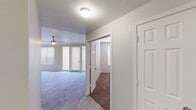 This well-appointed single-floor residence offers a thoughtfully designed layout that balances open living spaces with comfortable private areas. The living room is a standout feature, showcasing light wood-style flooring, a classic fireplace with a white mantel, a ceiling fan, and floor-to-ceiling windows flanking a patio door that floods the room with natural light. The kitchen is both functional and stylish, equipped with white shaker-style cabinetry, light quartz countertops, a subway tile backsplash in soft sage tones, stainless steel appliances including a range, built-in microwave, and dishwasher, as well as a double-basin sink. A built-in desk area adds a practical touch. The bedrooms are carpeted for comfort and each includes a ceiling fan and window with blinds, providing a quiet and restful atmosphere. The unit's open entry hallway connects the living and private areas seamlessly, with multiple closet doors visible for ample storage. Neutral wall tones and consistent finishes throughout give the space a cohesive, clean aesthetic. The overall ambiance is light, airy, and move-in ready, making it an inviting and versatile living environment.
