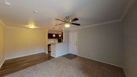 This single-floor residence offers a thoughtfully designed open-concept layout that seamlessly connects the living area and kitchen. The living room features plush carpeting, crown molding, and a ceiling fan, creating a comfortable and cohesive atmosphere. Hard-surface flooring transitions from the entryway into the kitchen, clearly delineating the functional zones of the space.

The kitchen is well-equipped with dark cabinetry, granite countertops, a subway tile backsplash, and stainless steel appliances including a microwave and dishwasher. A peninsula with pendant lighting above provides both additional prep space and a natural dividing point between the kitchen and living area. A sliding glass door in the living area allows for natural light and outdoor access.

The bedrooms are generously sized, each featuring soft carpeting, ceiling fans with built-in lighting, and windows that bring in natural light. The primary bedroom includes access to a walk-in closet, offering ample storage. The bathroom is fitted with a full tub-and-shower combination surrounded by clean white tile, wood-style flooring, and a built-in linen shelving unit for added organization. Overall, the space presents a functional and comfortable living environment with modern finishes throughout.