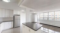 Located at 3967 Lawrence Avenue East in Toronto's Scarborough area, this 2-bedroom, 1-bathroom unit offers a well-organized single-floor layout with a clean, modern aesthetic throughout. The open-concept kitchen and living area form the heart of the unit, featuring a fully updated kitchen with white shaker-style cabinetry, subway tile backsplash, dark countertops, stainless steel appliances including a refrigerator, stove, and built-in microwave, and gleaming light tile flooring. A breakfast bar peninsula adds additional prep and dining space, with a seamless view into the living area beyond. The spacious living room is bathed in natural light through a large multi-panel window offering urban views, with rich hardwood-style flooring that runs through the main living and bedroom areas. Both bedrooms are generously sized, each featuring wide windows with baseboard heating beneath and parquet-style hardwood floors. The primary bedroom includes a mirrored sliding-door closet that enhances the sense of space. The bathroom is finished with classic white subway tile surrounding a full soaking tub. Crisp white walls and clean lines throughout give the unit a bright, move-in-ready feel.