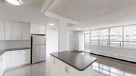 Located at 3967 Lawrence Avenue East in Toronto's Scarborough area, this 2-bedroom, 1-bathroom unit offers a well-organized single-floor layout with a clean, modern aesthetic throughout. The open-concept kitchen and living area form the heart of the unit, featuring a fully updated kitchen with white shaker-style cabinetry, subway tile backsplash, dark countertops, stainless steel appliances including a refrigerator, stove, and built-in microwave, and gleaming light tile flooring. A breakfast bar peninsula adds additional prep and dining space, with a seamless view into the living area beyond. The spacious living room is bathed in natural light through a large multi-panel window offering urban views, with rich hardwood-style flooring that runs through the main living and bedroom areas. Both bedrooms are generously sized, each featuring wide windows with baseboard heating beneath and parquet-style hardwood floors. The primary bedroom includes a mirrored sliding-door closet that enhances the sense of space. The bathroom is finished with classic white subway tile surrounding a full soaking tub. Crisp white walls and clean lines throughout give the unit a bright, move-in-ready feel.