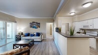 This thoughtfully designed 2-bedroom, 2-bathroom residence offers a comfortable and functional single-floor layout. The open-concept living, dining, and kitchen area creates a welcoming central hub, highlighted by wood-look plank flooring, crown molding, and a corner fireplace with a classic white mantel. The galley-style kitchen is well-equipped with white cabinetry, dark granite-look countertops, a full suite of white appliances, and ample storage on both sides of the corridor.

The dining area flows naturally from the kitchen and living room, providing a defined yet connected space for meals. The primary bedroom is generously sized, featuring plush carpet, a ceiling fan, natural light from large windows with sheer curtains, and direct access to a private bathroom and closet. The second bedroom is equally bright, with large windows and comfortable proportions. Both bathrooms feature white vanities and light, neutral finishes.

Additional highlights include a dedicated in-unit laundry area with overhead shelving, two closets for ample storage, and a private balcony. Throughout the residence, warm neutral tones and consistent finishes create a cohesive and inviting ambiance.