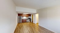 This one-bedroom, one-bathroom unit in Columbus, Ohio offers a practical and comfortable layout across a single floor. The open-concept kitchen and living area forms the heart of the unit, featuring warm hardwood-style flooring throughout. The kitchen is equipped with stainless steel appliances — including a refrigerator, electric range, and dishwasher — complemented by rich wood cabinetry and a skylight overhead that draws in natural light. The living area provides an open, airy feel with neutral walls and ample room for furnishing. The bedroom is a well-proportioned retreat finished with plush carpeting, a ceiling fan with integrated lighting, a window with exterior views, and a closet for storage. A second closet elsewhere in the unit adds additional storage convenience. The bathroom features clean, functional finishes, and the unit also includes a dedicated utility room housing the water heater. Textured ceilings carry throughout the space, and the consistent use of light, neutral tones creates a cohesive and welcoming atmosphere. A wall-unit HVAC provides in-unit climate control. This unit offers a straightforward, well-organized floor plan suited for comfortable everyday living.