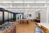 Located at 2600 W 3800 S in West Valley City, Utah, this single-floor community amenity space offers a thoughtfully designed environment for recreation and socializing. The room is defined by striking coffered ceilings finished in crisp white, which lend architectural character and a sense of height throughout the open layout. Rich light-toned hardwood flooring runs continuously underfoot, complementing the bold navy accent walls that anchor the space with a modern, energetic aesthetic.

The game area takes center stage, featuring both a full-size pool table and a foosball table, alongside a long counter-height bar ledge with industrial-style stools — ideal for spectating or casual gathering. A large Connect Four game and additional tabletop games add to the recreational variety. Frosted glass sliding partitions provide optional separation, offering flexibility in how the space is used.

A compact but well-equipped kitchenette supports entertaining, complete with stainless steel appliances including a French door refrigerator and dishwasher, a white tile backsplash, and a central island with counter seating. Cozy nook seating with a small bistro table rounds out the lounge area.

Expansive floor-to-ceiling sliding glass doors flood the interior with natural light and open directly onto an outdoor courtyard patio, creating a seamless indoor-outdoor connection ideal for community events and relaxed gatherings.
