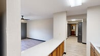 This well-appointed 4-bedroom, 2-bathroom single-floor unit offers a practical and comfortable layout designed to maximize living space. The combined kitchen and living area serves as the heart of the home, with the kitchen featuring warm oak cabinetry, white countertops, a stainless steel range, refrigerator, and a double sink — all illuminated by a skylight overhead. A peninsula counter separates the kitchen from the open living area, which is finished with durable light wood flooring and a ceiling fan. The bedrooms vary in size, with the generously proportioned primary bedroom offering ample space for furnishings. Bedroom floors feature a mix of light wood and plush carpet, and several rooms are equipped with ceiling fans and wall-unit air conditioners for year-round comfort. Select bedrooms include built-in closets with bifold doors. The two bathrooms are efficiently designed, each featuring a vanity with wood cabinetry, a mirror, and a shower-tub combination. One bathroom connects directly to a bedroom, adding a degree of privacy. Throughout the unit, neutral wall tones, dark accent baseboards, and consistent flooring choices create a cohesive and clean aesthetic.