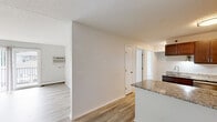 Located at 618 W Bridge St in Owatonna, Minnesota, this well-appointed 2-bedroom, 1-bathroom unit offers a practical and comfortable single-floor layout. The open-concept kitchen and living area serves as the heart of the home, featuring light luxury vinyl plank flooring throughout. The kitchen is equipped with rich dark-stained cabinetry, granite countertops, stainless steel appliances including an electric range and refrigerator, and a peninsula that provides additional prep space and separates the kitchen from the living area. The living room is bright and airy, highlighted by a sliding glass door that opens to a private balcony, allowing natural light to fill the space. Both bedrooms are carpeted for warmth and comfort, each featuring a ceiling fan, natural light from windows with blinds, and baseboard heating. The primary bedroom offers a comfortable, well-proportioned layout. The shared full bathroom continues the granite countertop theme with a large vanity mirror, an updated vanity, and a shower-tub combination. A dedicated closet provides additional storage. The unit's neutral color palette and consistent finishes create a clean, cohesive aesthetic throughout.