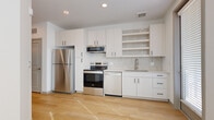 Located at 2125 E Apache Blvd in Tempe, Arizona, this efficiently designed unit offers a clean, contemporary aesthetic across a single floor. Light wood-style flooring extends throughout the entire space, lending warmth and visual continuity to every room.

The entryway hallway features frosted glass-paneled doors with gold hardware, recessed lighting, and a clean white palette that sets the tone for the rest of the unit. The kitchen is well-appointed with white shaker-style cabinetry, open shelving, a tiled backsplash, and a full suite of stainless steel appliances including a refrigerator, electric range, microwave, and dishwasher — offering ample functionality in a compact footprint.

The living area is bright and open, benefiting from natural light and a ceiling fan overhead, creating a comfortable and airy atmosphere. Large windows fitted with white horizontal blinds allow for adjustable light control throughout the space.

The bathroom is thoughtfully finished with a full tub-shower combo featuring vertical subway tile surround, a floating vanity with white countertop and black hardware, and consistent wood-look flooring. A closet provides dedicated storage, while the balcony offers an outdoor extension of the living space. The overall design is modern, minimal, and move-in ready.