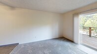 Located at 10550 SW Butner Rd in Portland, Oregon, this two-bedroom, two-bathroom apartment is thoughtfully arranged across two floors, offering a practical and comfortable living environment. The main floor houses the kitchen and living room, while the upper floor accommodates the bedrooms and additional bathroom, connected by two staircases for convenient access.

The kitchen is well-equipped with warm wood cabinetry, gray laminate countertops, a peninsula with additional prep space, a white electric range, dishwasher, and refrigerator. A skylight and window bring in natural light, creating a bright and functional cooking space. The adjacent living room features soft carpeting and access to natural light through a sliding panel.

Both bedrooms are carpeted and feature large windows that invite natural light and outdoor views of surrounding greenery. The spacious primary bedroom includes dual closets, providing generous storage. The second bedroom features a neutral color palette and its own window with pleasant outdoor views.

The two bathrooms are clean and functional. One features a vanity with wood cabinetry and a gray countertop with a mirrored medicine cabinet, while the other includes a full tub-shower combination with light wood-style flooring. Neutral tones and textured ceilings carry throughout the unit, giving the space a cohesive and understated aesthetic.