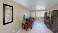 This single-floor residence at Sanford Estates Apartments offers a practical and comfortable layout across several distinct living spaces. The living room provides a welcoming entry point, featuring light tile flooring, a textured ceiling, and a large window with vertical blinds that allows natural light to fill the space.

The kitchen is efficiently designed with warm wood cabinetry, granite-style countertops, and white appliances including a refrigerator and electric range. A window above the sink adds natural light, and the layout maximizes available counter and storage space. Notably, a washer is conveniently accessible within or adjacent to the kitchen area.

A dedicated laundry room includes a full-size washer and dryer, an utility sink with granite-style counters, overhead wood cabinetry, and a bright window — offering practical storage and functionality.

The dining area accommodates a full dining set and benefits from natural light through a large windowed wall with vertical blinds. The unit includes multiple bedrooms, each finished with carpet flooring, neutral warm-toned walls, and windows with vertical blinds. The bathroom features tile flooring, a vanity with white cabinetry, and a tub-shower combination. Throughout, the unit maintains a consistent, neutral palette creating a cohesive and livable atmosphere.