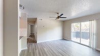 This 2-bedroom, 2-bathroom single-story residence offers a thoughtfully designed layout that maximizes functionality throughout. The open-concept living and dining area serves as the heart of the home, featuring light-toned luxury vinyl plank flooring, a textured ceiling, and a ceiling fan that enhances airflow and comfort. A sliding glass door floods the space with natural light and leads to a private balcony with exterior views. The kitchen is a standout feature, outfitted with crisp white shaker-style cabinetry, dark countertops, a subway tile backsplash, stainless steel appliances, and a single-basin sink — all complemented by light hardwood-style flooring. A pass-through opening connects the kitchen to the living area, reinforcing the open feel of the space. Both bedrooms are well-proportioned, each with ceiling fans, neutral-toned walls, and windows that bring in natural light. The primary bedroom includes a closet with bifold doors and built-in shelving for organized storage. The two bathrooms each feature a full tub-shower combination with white tile surrounds and chrome fixtures, maintaining a clean and consistent aesthetic throughout. A hallway connects all rooms efficiently, completing this practical and comfortable floor plan.