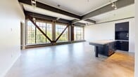 This 1,370 square foot loft-style apartment in Sacramento showcases a seamless blend of modern amenities and industrial charm. The open-concept layout maximizes the space, with exposed wooden beams and metal trusses adding character to the high ceilings. Large windows flood the interior with natural light, offering picturesque views of the surrounding cityscape.

The kitchen is a chef's delight, boasting sleek stainless steel appliances, contemporary cabinetry, and a spacious island with a concrete countertop. The color palette of cool blues and grays creates a sophisticated atmosphere.

The bedroom, measuring 250 square feet, provides a generous retreat. Two well-appointed bathrooms feature modern fixtures and glass-enclosed showers, with one showcasing a unique concrete floor.

Throughout the apartment, polished concrete floors add to the industrial aesthetic while providing durability and easy maintenance. The living area is versatile, perfect for entertaining or relaxing, with ample space for customization.

Storage is thoughtfully integrated, with two closets and additional built-in shelving. The apartment's design expertly balances raw industrial elements with refined finishes, creating a unique and stylish living space in the heart of Sacramento.