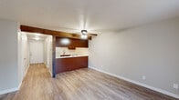 This two-story residence offers a well-organized layout designed for comfortable everyday living. The entry hallway features wood-look flooring that extends throughout the main level, leading toward a bright living area with a sliding glass door fitted with vertical blinds, allowing generous natural light to fill the space. A ceiling fan overhead adds both style and function to the living area.

The kitchen is defined by its warm, rich wood cabinetry, light quartz-style countertops, a stainless steel sink with a modern faucet, and a built-in dishwasher. A distinctive exposed wood beam adds architectural character, visually connecting the kitchen to the adjoining living area. The open pass-through design enhances the sense of flow between spaces.

The bathrooms are clean and functional, featuring a full tub and shower combination with grab bars, a vanity with ample counter space, and a window for ventilation. A convenient half bath is also present.

The bedrooms are located on the upper floor and are finished with plush carpeting, ceiling fans, and wide windows that invite views of the surrounding greenery. Additional rooms on the lower level feature durable wood-look flooring. Throughout the residence, neutral wall tones and textured ceilings create a cohesive and understated aesthetic.