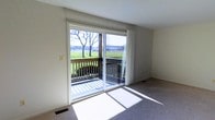 Located at 7099 Granada Dr in Flint, Michigan, this single-floor home offers a comfortable and functional layout with a clean, neutral aesthetic throughout. The living area is a standout feature of the home, finished with wall-to-wall carpeting and bathed in natural light that pours in through large sliding glass doors. These doors open directly onto a wooden deck, seamlessly connecting the interior to the outdoors. The deck offers open views of a green, landscaped yard and the surrounding landscape, making it an ideal spot for relaxing or entertaining. The interior walls are finished in a crisp, neutral tone that complements the light streaming in from the expansive glass doors, creating a bright and airy atmosphere. Floor vents throughout the living space indicate a forced-air climate control system, ensuring year-round comfort. The overall ambiance of the home is calm and inviting, with an emphasis on natural light and outdoor connectivity. The straightforward single-floor design provides easy accessibility and a cohesive flow throughout the space, making it a practical and pleasant place to call home.