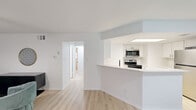 This contemporary 770 square foot apartment in Austin, TX offers a blend of style and functionality. The open-concept layout maximizes the use of space, with a combined dining room and kitchen that flows seamlessly into the living area. The kitchen boasts a modern design with white cabinetry, stainless steel appliances, and a convenient breakfast bar.

The living room is anchored by a plush gray sectional sofa, complemented by a striking geometric wallpaper feature wall. Large windows throughout allow for ample natural light, while ceiling fans in the bedrooms ensure comfort. The primary bedroom, measuring 140 square feet, features a bold red headboard and modern artwork.

The bathroom showcases a clean, minimalist design with a spacious vanity and light wood flooring. Both bedrooms offer cozy spaces with stylish lighting fixtures and ample closet space. The apartment's decor is a tasteful mix of modern and mid-century elements, with unique art pieces and a zebra-print rug adding character.

A standout feature is the dining area, which offers views of the community pool through large windows, perfect for enjoying meals or working from home. The apartment's location at 923 E 41st St puts residents in the heart of Austin, providing easy access to city amenities. With its thoughtful design and desirable features, this apartment offers a comfortable and stylish living experience in a vibrant urban setting.