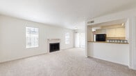 Located in Houston, TX, this 2-bedroom, 2-bathroom single-floor residence offers a well-organized layout designed for comfortable everyday living. The open-concept living and dining area serves as the heart of the home, featuring plush carpeting, bright white walls, and multiple windows that allow natural light to fill the space. A wood-burning fireplace with a tile surround and classic mantel acts as a focal point, adding warmth and character to the room. Sliding glass doors lead directly to a private balcony, extending the living space outdoors. The galley-style kitchen is efficiently designed with light hardwood flooring, white cabinetry, granite-look countertops, and black appliances including a refrigerator and range. A pass-through window connects the kitchen to the living and dining area, enhancing the open feel. Both bedrooms are carpeted and generously sized, each with natural light from windows and access to dedicated closet space — including a walk-in closet with built-in shelving. The two bathrooms mirror each other in style, featuring wood-look tile flooring, white vanities with granite-look countertops, and a tiled shower-tub combo. A hallway with additional closet storage provides practical organization throughout the home.
