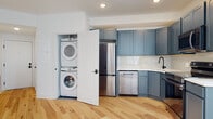 Located at The Bromley Loom House on N. Front Street in Philadelphia's vibrant 19133 neighborhood, this single-floor residence offers a thoughtfully designed layout with contemporary finishes throughout. Light natural hardwood flooring flows seamlessly across the living areas, creating a warm and cohesive aesthetic that complements the bright white walls and modern black window frames.

The kitchen is a standout feature, outfitted with slate-blue shaker-style cabinetry that provides generous storage, complemented by white countertops, a classic subway tile backsplash, and a full suite of stainless steel appliances including a refrigerator, range, built-in microwave, and dishwasher. A matte black sink fixture adds a refined, contemporary touch. Tall, narrow black-framed windows bathe the kitchen and adjacent living area in natural light, enhancing the open feel of the space.

A dedicated in-unit laundry closet houses a stacked washer and dryer, offering everyday convenience tucked neatly out of sight. The bathroom features bold large-format hexagonal tile flooring in a deep charcoal tone, crisp white subway-tiled walls surrounding the soaking tub and shower, and matte black fixtures that maintain a consistent modern design language throughout the unit. The bedroom is generously proportioned, with dual black-framed windows that invite natural light and a clean, versatile backdrop for furnishing.