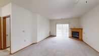 Located at 3280 Hillside Dr in Delafield, Wisconsin, this single-floor, two-bedroom, one-bathroom home offers a practical and comfortable layout with consistent finishes throughout. The combined kitchen and living room serves as the heart of the home. The living room is carpeted and bright, featuring a wood-trimmed corner fireplace and a sliding glass door that fills the space with natural light and provides outdoor access. The L-shaped kitchen is equipped with warm oak cabinetry, ample storage including a tall pantry cabinet, tile flooring, and white appliances including a range, microwave, dishwasher, and refrigerator. The primary bedroom is generously sized, benefiting from multiple windows that bring in natural light and views of the surrounding wooded landscape, along with access to a dedicated walk-in closet with wire shelving. The second bedroom is well-proportioned with its own window. The full bathroom features tile flooring, an oak vanity with storage drawers, and a window for natural light. A dedicated in-unit laundry area houses a stacked washer and dryer with an additional storage shelf. Warm wood trim and neutral tones carry consistently throughout, giving the home a cohesive and move-in-ready feel.