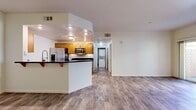 This single-floor residence offers a thoughtfully designed layout encompassing two bedrooms and two full bathrooms. The open-concept kitchen anchors the living space and is outfitted with warm honey-toned wood cabinetry, dark granite countertops, stainless steel appliances including a gas range, built-in microwave, French door refrigerator with ice and water dispenser, and a dishwasher. A peninsula with a dark countertop provides additional prep space and separates the kitchen from the carpeted living area. Light tile flooring runs throughout the kitchen, while plush neutral carpet extends into the living room and both bedrooms. A louvered pantry door adds a classic touch to the kitchen. The bedrooms are comfortably sized, featuring neutral walls, soft carpet, and wood-framed windows with horizontal blinds that allow natural light to filter in. Both bathrooms maintain a cohesive aesthetic with warm wood vanity cabinetry, dark granite countertops, undermount sinks, and light tile flooring. One bathroom includes a shower-tub combination with a window, while the other features a walk-in shower. A hallway connects the private sleeping quarters to the main living area, and the entryway opens directly into the spacious common area, completing the functional and coherent floor plan.