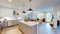 Located in Atlanta's vibrant Old Fourth Ward neighborhood, this single-floor residence at 652 Angier Ave NE offers a thoughtfully designed open-concept layout with contemporary finishes throughout. The kitchen serves as the heart of the home, featuring a large center island with seating, white quartz countertops, two-tone cabinetry, stainless steel appliances including a gas range and French door refrigerator, open shelving, and bold pendant lighting. An in-unit stacked washer and dryer is conveniently integrated into the kitchen area. The kitchen flows seamlessly into the living room, which is bathed in natural light from large windows dressed with sheer curtains. A ceiling fan and wood-look flooring carry through the open living space. The bedrooms offer generous proportions, each with large windows framing urban views, ceiling fans, and wood-look flooring. One bedroom features a striking accent wall, while another includes access to a spacious walk-in closet with built-in shelving and hanging systems. The bathroom is well-appointed with a dual-vanity, decorative wall panel, and a tub-shower combination. Clean lines, a neutral palette, and modern fixtures define the overall aesthetic of this well-equipped Atlanta residence.