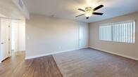 Located at 8605 N 59th Ave in Glendale, Arizona, this one-bedroom, one-bathroom unit offers a practical and well-organized single-floor layout. The living area transitions between wood-look laminate flooring and plush carpet, with a ceiling fan overhead providing year-round comfort. A dedicated kitchen features rich, dark wood cabinetry, light countertops, and a full suite of black appliances including a refrigerator, electric range, and over-the-range microwave. Recessed lighting and a tray ceiling detail add a subtle architectural touch to the kitchen space. The bedroom is a comfortable, carpeted retreat equipped with its own ceiling fan and a window fitted with vertical blinds that allow natural light while providing privacy and views of the surrounding greenery. The bathroom is clean and functional, featuring a full-size soaking tub with a shower combo, a white surround with built-in shelving, wood-look flooring, and classic brushed gold hardware accents. Throughout the unit, neutral white walls and white baseboards create a bright, cohesive aesthetic that is easy to personalize. This unit offers a straightforward, efficient living space well-suited for those seeking comfort and practicality in the Glendale area.