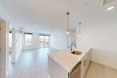 Located on the fifth floor at 42 N Beacon St in Boston's Allston neighborhood, this modern 2-bedroom, 2-bathroom residence offers a bright, thoughtfully designed living space with a clean, contemporary aesthetic throughout. Light wood-tone flooring flows seamlessly across the open floor plan, complemented by crisp white walls and recessed lighting that enhance the airy ambiance.

The open-concept kitchen and living area form the heart of the unit. The kitchen features a large island with white quartz countertops, a stainless steel undermount sink, sleek white cabinetry with brushed gold hardware, a subway tile backsplash, and stainless steel appliances including a dishwasher and range. Pendant lighting over the island adds a stylish finishing touch. The adjacent living area is generously proportioned, benefiting from natural light and direct access to a private balcony with city views.

Both bedrooms are well-sized, with the primary bedroom offering ample space, a wall-mounted split HVAC unit, and a window framing rooftop and skyline views. The second bedroom also features natural light and city-facing views. Two closets provide dedicated storage throughout the unit.

The bathrooms are finished with white subway tile surrounds, soaking tubs, and warm wood vanities with brushed gold fixtures. In-unit laundry adds further convenience, rounding out this well-appointed Boston residence.