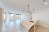 Located on the fifth floor at 42 N Beacon St in Boston's Allston neighborhood, this modern 2-bedroom, 2-bathroom residence offers a bright, thoughtfully designed living space with a clean, contemporary aesthetic throughout. Light wood-tone flooring flows seamlessly across the open floor plan, complemented by crisp white walls and recessed lighting that enhance the airy ambiance.

The open-concept kitchen and living area form the heart of the unit. The kitchen features a large island with white quartz countertops, a stainless steel undermount sink, sleek white cabinetry with brushed gold hardware, a subway tile backsplash, and stainless steel appliances including a dishwasher and range. Pendant lighting over the island adds a stylish finishing touch. The adjacent living area is generously proportioned, benefiting from natural light and direct access to a private balcony with city views.

Both bedrooms are well-sized, with the primary bedroom offering ample space, a wall-mounted split HVAC unit, and a window framing rooftop and skyline views. The second bedroom also features natural light and city-facing views. Two closets provide dedicated storage throughout the unit.

The bathrooms are finished with white subway tile surrounds, soaking tubs, and warm wood vanities with brushed gold fixtures. In-unit laundry adds further convenience, rounding out this well-appointed Boston residence.