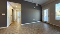 This contemporary 870 square foot apartment in Bloomington, Indiana offers a well-designed living space with two bedrooms and two bathrooms. The single-story layout maximizes functionality, featuring an open-concept living and kitchen area that creates a spacious feel.

The kitchen boasts dark wood cabinetry, contrasting beautifully with white subway tile backsplash and light countertops. Stainless steel appliances and pendant lighting add a modern touch. A central island with a sink provides additional prep space and casual seating.

Both bedrooms are generously sized, with the primary bedroom measuring 170 square feet. Large windows in the bedrooms and living area flood the space with natural light, while offering views of the surroundings. The bathrooms feature dark wood vanities with white countertops, and at least one includes a glass-enclosed shower.

Throughout the apartment, wood-look flooring in a warm tone unifies the space and adds a touch of elegance. The neutral gray wall color provides a versatile backdrop for various decor styles. Ample closet space and a dedicated hallway enhance the apartment's functionality.

This well-appointed apartment combines modern amenities with a practical layout, creating an inviting and comfortable living environment in a prime Bloomington location.