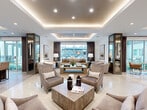 Located at 816 Addicks Howell Rd in Houston, TX, this sophisticated single-floor clubhouse serves as a premier amenity space defined by high-end finishes and a cohesive contemporary aesthetic. The open, generously proportioned layout is anchored by gleaming polished tile flooring that reflects the warm ambient glow of recessed lighting and elegantly tiered tray ceilings fitted with cove lighting throughout.

The main lounge area offers multiple thoughtfully arranged seating groupings, featuring plush upholstered armchairs and sofas in neutral tones, paired with stylish wood-and-stone coffee tables. Large floor-to-ceiling windows and glass doors frame direct views of an outdoor pool area, flooding the interior with natural light and creating a seamless indoor-outdoor connection enhanced by rich, floor-length draping.

A dedicated wet bar and entertainment zone features bar-height seating, a textured accent wall, and a large-screen TV, making it ideal for social gatherings. The billiards area accommodates a full-sized pool table beneath dramatic pendant lighting, complemented by bistro-style side tables and casual seating. Glass-paneled partition walls and mirrored columns add architectural depth, while curated décor and accessories throughout contribute to the space's polished, resort-inspired ambiance.