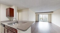 Located on the third floor at 200 S Van Dorn Street in Alexandria, Virginia, this one-bedroom unit offers a practical and well-organized layout. The combined kitchen and living area forms the heart of the home, featuring rich dark hardwood-style flooring that extends throughout the main living spaces. The kitchen is appointed with warm cherry-toned cabinetry, granite-patterned countertops, stainless steel appliances including a gas range and refrigerator, and light tile flooring — providing both functionality and style. A peninsula with a built-in sink opens the kitchen toward the living area, creating a connected and sociable flow. The living room is bright and airy, with large sliding glass doors that flood the space with natural light and lead directly to a private balcony. From the balcony, residents enjoy open views of the community's tennis courts and the surrounding Alexandria skyline. The spacious primary bedroom continues the hardwood-style flooring and also features sliding glass door access to the balcony, bringing in additional natural light and outdoor views. With four closets distributed throughout the unit, storage is plentiful. The textured ceilings and neutral wall tones provide a clean, move-in-ready canvas throughout the home.