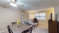 Located at 1450 Haft Dr in Reynoldsburg, Ohio, this single-floor residence offers a well-organized and comfortable layout across several distinct living areas. The living room is a welcoming space finished with neutral textured walls, crown molding, and soft wall-to-wall carpeting. A large window fitted with horizontal blinds allows natural light to fill the room, providing views of the surrounding exterior. Adjacent to the living room, the dining area features a ceiling fan with a light fixture and crown molding, comfortably accommodating a full dining set beneath a decorative circular wall mirror. The kitchen is equipped with dark wood cabinetry offering ample upper and lower storage, a gas range, and light countertops, all set atop tile flooring. The bedroom is a serene retreat with carpeted floors, textured neutral walls, a window for natural light, and coordinated bedside furnishings. A hallway connects the bedroom to a full bathroom, which includes a tub-shower combination, toilet, and tile flooring. A linen closet positioned between the bathroom and bedroom provides additional storage. Throughout the residence, a consistent warm, neutral color palette and carpet flooring create a cohesive and comfortable atmosphere.