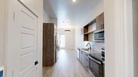 Located at 3700 Ross Avenue in Dallas, TX, this thoughtfully designed studio offers a compact yet efficient single-floor layout. Light wood-tone vinyl flooring flows seamlessly throughout the entire space, creating a warm, cohesive aesthetic against crisp white walls.

The kitchen is a standout feature, showcasing wood-grain cabinetry with matte black hardware, granite-look countertops with a white subway tile backsplash, and a full suite of stainless steel appliances including a refrigerator, range, microwave, and dishwasher. A deep single-basin sink with a matte black faucet anchors the galley-style workspace. Natural light filters in through a glass-paned front door, brightening the open living area beyond, which is accented by a ceiling fan and pendant lighting.

The bathroom is well-appointed with a soaking tub and shower combo, fully tiled surround walls in neutral gray, matte black fixtures, and a granite-top vanity that mirrors the kitchen's design language. A dedicated closet provides convenient built-in storage. Clean lines, neutral tones, and modern finishes give this space a polished, move-in-ready feel suited for urban living in the heart of Dallas.