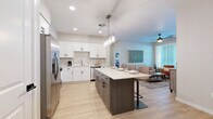 Located at 39695 W Lococo St in Maricopa, AZ, this single-story 2-bedroom, 2-bathroom home offers a thoughtfully designed layout with modern finishes throughout. The open-concept kitchen and living area serves as the heart of the home, featuring crisp white shaker cabinets, light quartz countertops, a central island with bar seating, stainless steel appliances, and pendant lighting. Light wood-look flooring flows seamlessly through the main living areas, complementing the clean, contemporary aesthetic. The living room is bright and welcoming, with large windows dressed in white blinds that invite natural light, a ceiling fan, and easy access to the front entry. Both bedrooms are carpeted and comfortably sized, each with windows providing natural light. The primary bedroom includes a dedicated closet. The two bathrooms maintain the home's modern theme, with white cabinetry, clean countertops, and light wood-look flooring. One features a full shower with an arched niche surround, while the other includes a tub-shower combination. Neutral wall tones and consistent finishes throughout create a cohesive, move-in-ready atmosphere well-suited to the sunny Maricopa, AZ environment.