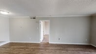 This single-floor, one-bedroom, one-bathroom unit in Houston, TX (77096) offers a well-organized layout designed for efficient, comfortable living. The living area features wood-style flooring, neutral gray walls, crown molding, and a textured ceiling, lending a clean and cohesive aesthetic throughout. A sliding glass door floods the space with natural light while providing outdoor views, and a HVAC vent ensures climate control year-round.

The kitchen is configured as a galley-style space, equipped with white cabinetry, speckled granite-look countertops, a double-basin sink, a black refrigerator, and a black gas range with dishwasher. A pass-through counter with overhead cabinetry connects the kitchen to the adjacent living and dining area, enhancing the open feel of the floor plan.

The bedroom is carpeted for comfort and features a ceiling fan with integrated lighting, a window with blinds for natural light, and neutral-toned walls. The 3D floor plan confirms the logical flow between living, kitchen, and bedroom areas, with convenient access to the bathroom and additional closet storage. Overall, the unit presents a tidy, functional environment suited for practical everyday living.