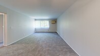 Located at 195 W Kennett Rd in Pontiac, Michigan, this single-floor, two-bedroom, one-bathroom unit offers a practical and comfortable layout. The open-concept living and kitchen area features a combination of wood-style hard flooring and plush carpet, with warm-toned cabinetry, a refrigerator, and a convenient pass-through kitchen setup that connects to the main living space. A ceiling fan adds comfort to this area, while vertical blinds on large windows allow for adjustable natural light. A wall-mounted HVAC unit and baseboard heating provide year-round climate control throughout the home. The generously sized primary bedroom is carpeted and includes a large double closet, offering ample storage. The second bedroom is also carpeted and features a window with vertical blinds and baseboard heating, creating a bright and cozy space. Both bedrooms maintain a clean, neutral palette. The bathroom is fitted with a full tub-shower combo lined with classic white square tile, lending a clean and timeless look. A connecting hallway ties the rooms together efficiently. Overall, the unit presents a functional, move-in-ready layout suited for everyday living.