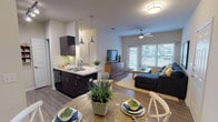 This 2-bedroom, 1-bathroom residence is thoughtfully laid out across a single floor, maximizing functionality and comfort throughout. The open-concept living and dining area is anchored by wood-style plank flooring, a ceiling fan, and large windows fitted with blinds that allow ample natural light while maintaining privacy. The living space flows seamlessly into the dining area, which features a warm, intimate setting with decorative wall art.

The kitchen is designed for efficiency, featuring dark espresso cabinetry, light granite-style countertops, black appliances including a refrigerator and range, a double-basin sink, and track lighting overhead. A peninsula with pendant lighting bridges the kitchen and dining space, enhancing the open feel.

The primary bedroom is a restful retreat with a ceiling fan, wood-style flooring, a window with natural light, and access to a spacious walk-in closet. The second bedroom mirrors this comfort with its own ceiling fan, closet, and a bright window. Both rooms offer a quiet, well-proportioned feel.

The full bathroom is clean and functional, featuring a dark vanity with granite-style countertops, a tub-shower combination, and wood-style flooring. The cohesive design palette of neutral tones, dark cabinetry, and wood-style flooring ties the entire residence together with a modern, polished aesthetic.
