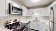 This single-floor residence showcases a thoughtfully updated interior with a cohesive neutral color palette and modern finishes throughout. The open living areas feature durable wood-look hard flooring in cool gray tones, complemented by textured ceilings and crisp white trim that lend a clean, contemporary feel.

The kitchen stands out as a highlight of the space, outfitted with bright white shaker-style cabinetry, white subway tile backsplash, and light quartz countertops. Stainless steel appliances — including an electric range, over-the-range microwave, and dishwasher — complete the functional and stylish cooking area.

The bedrooms offer a comfortable retreat with plush neutral carpeting underfoot, generous closet space, and windows that allow natural light to filter in. The textured ceilings carry throughout these rooms, maintaining a consistent design language across the residence.

The bathroom is well-appointed with a wide white vanity offering ample storage, a light quartz countertop, an undermount sink with brushed nickel fixtures, and a framed mirror illuminated by a modern multi-bulb vanity light. The overall ambiance of this residence is clean, move-in ready, and modern, making it a practical and attractive living space.