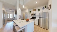 Located on Orchard View Drive in Rochester, NY, this well-appointed 2-bedroom, 2-bathroom single-floor home offers a thoughtfully designed open-concept layout with a bright, airy atmosphere throughout. Light wood-style flooring flows across the main living areas, complemented by vaulted ceilings that enhance the sense of spaciousness.

The kitchen is a standout feature, boasting white cabinetry, stainless steel appliances, and a large center island with bar seating and pendant lighting overhead — ideal for both meal prep and casual dining. The adjacent dining area provides a defined space for entertaining, while the living room is anchored by a tile-surround fireplace and large windows that draw in generous natural light and neighborhood views.

The generously sized primary bedroom features plush carpeting, vaulted ceilings, and multiple windows, creating a comfortable and serene retreat. The second bedroom also benefits from ample natural light. Both bathrooms are finished cleanly, with one featuring a glass-enclosed walk-in shower and wood-style flooring.

Additional highlights include a dedicated in-unit laundry room with full-size washer and dryer, overhead cabinetry for storage, and two closets. The overall design balances functionality and comfort, making this a practical and inviting home.