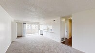 Located at 2098 West Acacia Avenue in Hemet, CA, this single-floor home offers four bedrooms and two bathrooms across a well-organized layout. The open-concept living room and kitchen area forms the heart of the home, bathed in natural light through large sliding glass doors that lead to a private balcony with views of the surrounding neighborhood. The living area features plush carpeting and a textured ceiling, creating a comfortable and inviting atmosphere.

The kitchen is equipped with white cabinetry, light granite-style countertops, a gas range, dishwasher, and a double-basin sink positioned beneath a window. Wood-style flooring runs through the kitchen, adding warmth and contrast to the bright, clean design.

The four bedrooms are carpeted and feature neutral white walls, textured ceilings, and windows that allow natural light to filter in. The primary bedroom is generously sized and includes a spacious closet with dual hanging rods for ample storage.

Both bathrooms are clean and functional, each featuring a full tub-and-shower combination with white tile surround and brushed nickel fixtures. One bathroom includes wood-style flooring, while both maintain a bright, neutral aesthetic. A hallway connects the bedroom wing to the main living areas, completing this practical and comfortable floor plan.