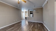 This well-appointed 2-bedroom, 2-bathroom home in Round Rock, TX offers a thoughtfully designed single-story layout. Dark wood-look flooring flows throughout the entire unit, providing a cohesive and modern aesthetic. The open-concept living area is bright and welcoming, featuring crown molding, a ceiling fan, and neutral taupe walls that complement the flooring. A pendant light highlights the pass-through kitchen, which includes stainless steel appliances — refrigerator and range — dark cabinetry, and a built-in desk or shelving nook, offering both functionality and style. The bedrooms are comfortable and well-lit, each with windows that bring in natural light and views of surrounding greenery. The primary bedroom includes access to a spacious walk-in closet outfitted with wire shelving and hanging rods on multiple walls for generous storage. Both bathrooms are finished with dark wood vanity cabinetry, white countertops, brushed nickel hardware, and tub-shower combinations with tiled surrounds. A dedicated laundry area accommodates a full-size washer and dryer side by side. The entrance provides a welcoming transition into the home, completing a practical and comfortable layout suited for everyday living in Round Rock, Texas.