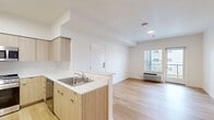 Located at 11603 NE 71st St in Vancouver, WA, this single-floor, 3-bedroom, 2-bathroom unit offers a thoughtfully designed layout with a modern aesthetic. The open-concept kitchen and living area serves as the heart of the home, anchored by a peninsula with a white countertop and an undermount sink. The kitchen is well-appointed with light wood cabinetry extending to the ceiling, a stainless steel refrigerator, gas range, built-in microwave, and dishwasher — providing both functionality and style. Light wood-tone flooring runs throughout the main living areas, complementing the crisp white walls and creating a bright, airy atmosphere. A window in the living area allows natural light to fill the space. The three bedrooms are carpeted for comfort, with the spacious primary bedroom offering generous closet space. The secondary bedrooms are well-sized and share access to the hallways connecting the unit. Both bathrooms feature clean, modern finishes, including wood-toned vanities, white countertops, large mirrors, and light fixtures above. A balcony provides outdoor access with views of the surrounding community. The unit's clean lines, neutral palette, and modern fixtures make it a comfortable and functional living space.