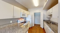 This single-floor, one-bedroom, one-bathroom residence in Memphis, TN offers a well-organized layout designed for comfortable living. The kitchen is equipped with white cabinetry, granite-style countertops, and a full suite of white appliances including an electric range, over-the-range microwave, and refrigerator. Rich hardwood-style flooring runs throughout the kitchen, adding warmth and visual continuity to the space.

A hallway connects the kitchen to the living area, featuring built-in open shelving—ideal for storage or display. The living room is carpeted and finished with crown molding, a ceiling fan with light fixture, and multiple windows that invite natural light. A glass-paneled exterior door provides additional brightness and outdoor access.

The bedroom is spacious and carpeted, accented with crown molding and a ceiling fan, creating a calm and functional retreat. The bathroom is finished with hardwood-style flooring, a granite-topped vanity with under-sink cabinetry, a large wall mirror with a multi-bulb vanity light fixture, and a shower/tub combination. Neutral gray tones throughout the bathroom create a clean, contemporary feel. Overall, the unit presents a cohesive and practical design suited for single-occupancy living in Memphis.