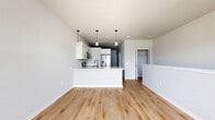 Located at 1211 Carrington Blvd in Mount Pleasant, WI, this thoughtfully designed 600 square foot single-floor apartment offers a clean, modern aesthetic throughout. The open-concept kitchen and living area serves as the heart of the unit, featuring two-tone cabinetry with white upper cabinets and gray lower cabinets, quartz countertops with subtle veining, a stainless steel undermount sink with a matte black faucet, and stainless steel appliances including a range, microwave, and French door refrigerator. Stylish pendant lighting accents the kitchen island, which provides additional prep and seating space. Light hardwood flooring flows seamlessly throughout the main living areas, complementing the neutral gray-toned walls. The living area benefits from a large triple-pane window and a glass door that opens to an outdoor deck, filling the space with natural light and exterior views of the surrounding community. The bathroom is finished with matching gray cabinetry, white quartz countertops, black hardware accents, and hardwood-style flooring. The dedicated walk-in closet features a full wire shelving and basket organization system with carpeted flooring, maximizing storage efficiency within the unit's compact footprint.