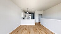 Located at 1211 Carrington Blvd in Mount Pleasant, WI, this thoughtfully designed 600 square foot single-floor apartment offers a clean, modern aesthetic throughout. The open-concept kitchen and living area serves as the heart of the unit, featuring two-tone cabinetry with white upper cabinets and gray lower cabinets, quartz countertops with subtle veining, a stainless steel undermount sink with a matte black faucet, and stainless steel appliances including a range, microwave, and French door refrigerator. Stylish pendant lighting accents the kitchen island, which provides additional prep and seating space. Light hardwood flooring flows seamlessly throughout the main living areas, complementing the neutral gray-toned walls. The living area benefits from a large triple-pane window and a glass door that opens to an outdoor deck, filling the space with natural light and exterior views of the surrounding community. The bathroom is finished with matching gray cabinetry, white quartz countertops, black hardware accents, and hardwood-style flooring. The dedicated walk-in closet features a full wire shelving and basket organization system with carpeted flooring, maximizing storage efficiency within the unit's compact footprint.