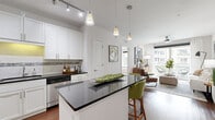 Located in the heart of downtown Orlando on N Orange Ave, this well-appointed 2-bedroom, 2-bathroom residence offers a thoughtfully designed open-concept layout. The kitchen is a standout feature, showcasing crisp white shaker cabinetry, dark granite countertops, a mosaic tile backsplash, stainless steel appliances, and a central island with pendant lighting — ideal for both cooking and casual dining. Rich hardwood flooring flows seamlessly into the living room, which is bathed in natural light from expansive floor-to-ceiling sliding glass doors that open onto a private balcony with views of the surrounding cityscape. A ceiling fan adds comfort to this bright, airy gathering space. Both bedrooms offer carpeted floors, generous natural light through large windows, and dedicated closets — including a spacious walk-in closet. The primary bathroom is well-equipped with a dual-sink vanity topped in speckled granite, a glass-enclosed shower, and wood-toned tile flooring. A second full bathroom provides added convenience. Two additional closets offer ample storage throughout. Clean lines, neutral tones, and modern finishes create a cohesive and contemporary ambiance throughout this downtown Orlando residence.