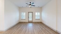 Located at 91 Wiltons Way in Bluffton, SC, this one-bedroom, one-bathroom residence offers a well-designed single-floor layout that maximizes functionality and comfort. The open-concept kitchen and living area serves as the heart of the home, featuring light wood-style flooring, a ceiling fan, and a glass door that opens to a private balcony, allowing natural light to flow in from multiple windows. The kitchen is a standout, equipped with gray shaker-style cabinetry, white quartz countertops, stainless steel appliances including a range, microwave, and refrigerator, and a striking navy blue island with a built-in sink and pendant lighting above—adding a bold design accent to the otherwise neutral palette. In-unit stacked laundry is also conveniently located within the main living area. The bedroom is a comfortable retreat finished with plush carpeting, a ceiling fan, and windows with blinds that provide natural light and neighborhood views. The bathroom is clean and modern, featuring a vanity with white countertop, wood-look tile flooring, and a glass-enclosed walk-in shower with white subway tile. A dedicated closet completes the layout, offering practical storage. The overall aesthetic is bright, contemporary, and move-in ready.