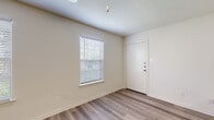This single-floor residence offers a clean, contemporary layout designed for comfortable everyday living. The entry opens into a bright living area finished with durable wood-look luxury vinyl plank flooring, neutral-toned walls, and natural light streaming through horizontal-blind-fitted windows. A pass-through counter connects the living space to the kitchen, which is outfitted with gray shaker-style cabinetry, white quartz countertops, and a full suite of stainless steel appliances including a refrigerator, electric range, over-the-range microwave, and dishwasher. The light-toned LVP flooring continues throughout the kitchen, enhancing the bright, modern aesthetic. The bedrooms feature soft wall-to-wall carpeting and well-sized windows that invite natural light, creating a comfortable and restful atmosphere. One bedroom includes a closet with a paneled door. The bathroom is finished with wood-look flooring, a full tub-and-shower combination clad in large-format gray tiles, brushed nickel fixtures, and a vanity with ample cabinet storage. Throughout the residence, clean white trim, textured ceilings, and a cohesive neutral color palette create a move-in-ready environment that is both functional and inviting.