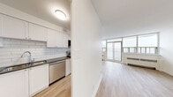 Located on the 8th floor at 2050 Keele Street in Toronto's Mount Dennis neighbourhood, this one-bedroom, one-bathroom unit offers a well-organized layout with light hardwood flooring throughout. The open living area is bright and spacious, featuring floor-to-ceiling windows and sliding glass doors that lead to a private balcony with sweeping views of the Toronto skyline and surrounding greenery. Natural light fills the space generously throughout the day.

The kitchen is thoughtfully designed with white shaker-style cabinetry extending to the ceiling, a light blue subway tile backsplash, dark countertops, a stainless steel refrigerator, and a built-in dishwasher — offering both style and functionality.

The bedroom is a comfortable, well-proportioned room featuring large windows that continue the unit's access to natural light and city views, along with a sliding door closet for ample storage.

The bathroom is finished with full white subway tile surrounding a soaker tub and shower combination, complemented by a clean white vanity and sink.

A welcoming hallway connects all areas of the unit, completing a practical and cohesive floor plan. The crisp white walls and warm flooring throughout create a clean, modern ambiance.