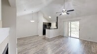 This well-designed one-bedroom, one-bathroom unit offers an efficient and comfortable layout across a single floor. The open-concept living, dining, and kitchen area is the centerpiece of the home, highlighted by soaring vaulted ceilings that lend a spacious, airy feel well beyond the unit's physical footprint. Wood-look plank flooring runs throughout the main living areas, complemented by neutral white walls that maximize natural light. A ceiling fan with integrated lighting adds both comfort and style. A standout feature of the living area is the tile-surround fireplace, which anchors the space with warmth and character. Sliding glass doors open onto a private balcony with leafy outdoor views, seamlessly connecting the interior to the outside. The kitchen features dark cabinetry with a contrasting light countertop peninsula, stainless steel appliances, and ample cabinet storage. Two closets provide generous storage solutions throughout the unit. The bedroom is a quiet retreat with plush carpet flooring, a ceiling fan, and a large window that fills the room with natural light. The bathroom is clean and functional, offering a full tub/shower combo, a dark-vanity with a white countertop sink, and wood-look flooring. A dedicated laundry area adds everyday convenience to this thoughtfully appointed home.