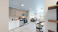 Located on Massachusetts Ave in Amherst, MA, this thoughtfully designed 2-bedroom, 2-bathroom residence offers a modern and efficient layout across a single floor. The open-concept kitchen and living area serves as the heart of the home, featuring light wood cabinetry, stainless steel appliances including a refrigerator, range, microwave, and dishwasher, and a clean white countertop. Light wood-tone flooring runs seamlessly throughout, enhancing the bright and airy atmosphere. A dining area sits adjacent to the kitchen, while the living room offers a welcoming space with a large window that brings in natural light and views of the surrounding neighborhood. Both bedrooms are comfortably appointed with windows providing natural light, built-in closet shelving, and ample storage. The two bathrooms feature light wood vanities, white countertops, and light flooring, maintaining the cohesive contemporary aesthetic. A dedicated in-unit laundry area is equipped with a full-size side-by-side washer and dryer alongside built-in shelving for added convenience. The overall design emphasizes clean lines, neutral tones, and functional use of space, creating a modern and comfortable living environment.